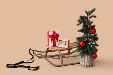İçinde saksıda Noel ağacı, hediye kutusu ve bej arka planda küp takvimi var.