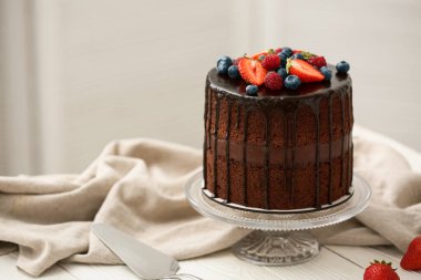 Mutfaktaki masada taze böğürtlenli ve spatulalı lezzetli çikolatalı pasta.