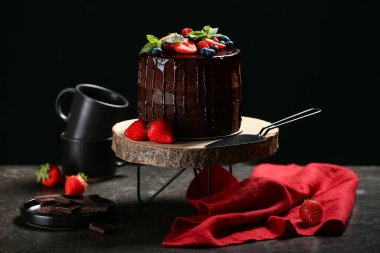 Lezzetli çikolatalı pasta taze böğürtlenli ve grunge masasında siyah arka planda.