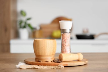 Kabuklu ahşap havan topu, biber ve deniz tuzu mutfakta, yakın plan.