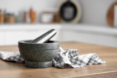 Mutfaktaki masada tokmak ve peçeteli granit havan topu, yakın plan.