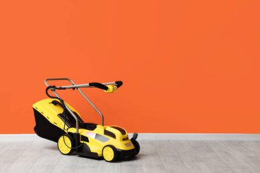 Çim biçme makinesi turuncu duvarın yanında.