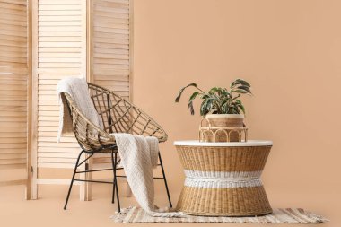 Renkli masa ve bej arka planda ahşap katlanır ekran ile hasır koltuk