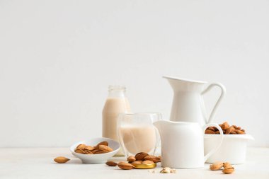 Beyaz arka planda fındıklı bir bardak taze badem sütü.
