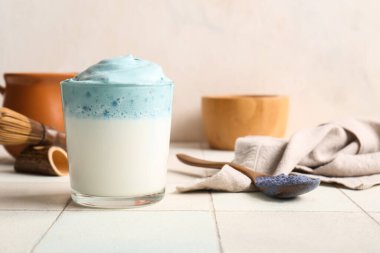 Bir bardak mavi dalgona latte, peçete ve kaşık fayans masasında, yakın plan.