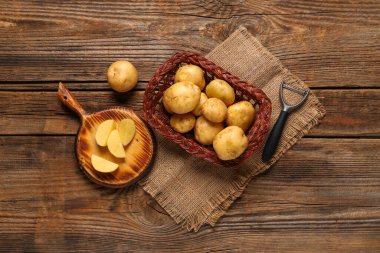 Hasır sepet ve tahta arka planda çiğ patates.