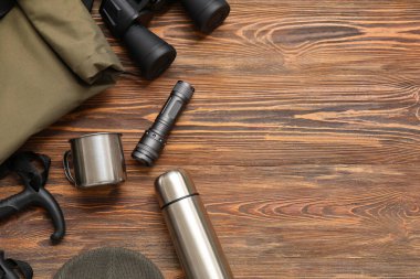 Modern termosa sahip kompozisyon ve ahşap arka planda seyahat için farklı öğeler