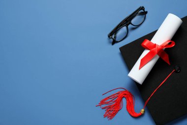 Mezuniyet şapkası, gözlükler ve mavi arka plan diploması.