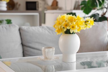 Mutfaktaki masada nergisli vazo ve bir fincan kahve, yakın plan.