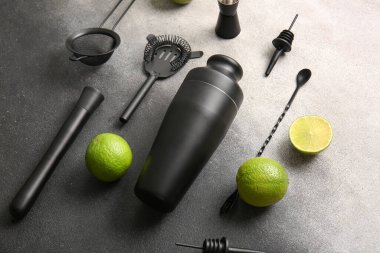 Gri grunge arka planda limonlu farklı barmen aletleri.