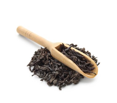 Beyaz arka planda bir yığın kuru siyah çay yapraklı ahşap kepçe.