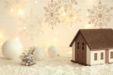 Süslü ev, kar taneleri, Noel topları, tümsekler ve beyaz ahşap arka planda kar
