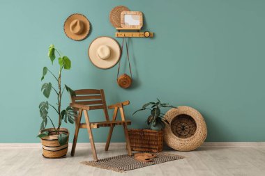 Odanın içinde ahşap sandalye, ev bitkileri, hasır sepet ve mavi duvardaki raf.