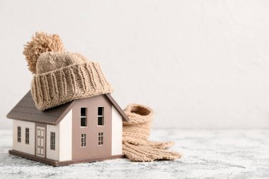 Kış kompozisyonu dekoratif ev, sıcak eşarp ve beyaz arka planda grunge masasında şapka