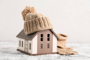 Kış kompozisyonu dekoratif ev, sıcak eşarp ve beyaz arka planda grunge masasında şapka