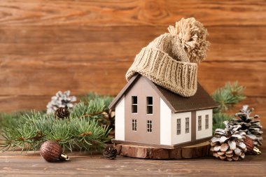 Dekoratif evi olan kış kompozisyonu, orman çıkıntıları, kahverengi ahşap arka planda köknar ağacı dalları ve şapka.