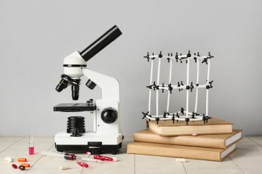 Mikroskop, kitaplar, ampuller ve gri arkaplan üzerinde haplar olan moleküler model. Nobel Ödül Günü