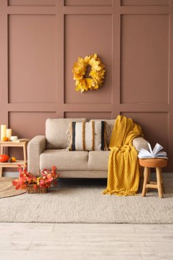 Sonbahar dekoru, rahat kanepesi ve taburesi olan bir oturma odası.
