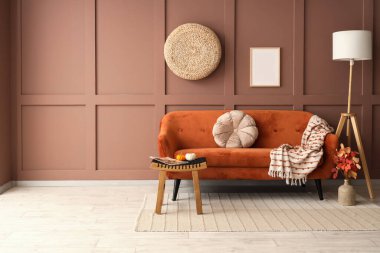 Sonbahar dekoru, rahat kanepesi ve zemin lambası olan bir oturma odası.