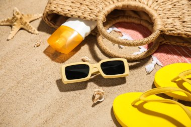 Arka planda güneş kremi, deniz kabuğu ve kumsal aksesuarları olan kompozisyon, yakın plan.