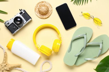Kamera, kulaklık ve bej arka planda plaj aksesuarları olan cep telefonu.