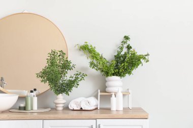 Lavabonun yanında yeşil dalları olan bir banyo.