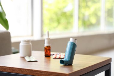 Modern astım spreyi, haplar ve ilaçlar oturma odasındaki sehpanın üzerinde, yakın plan.