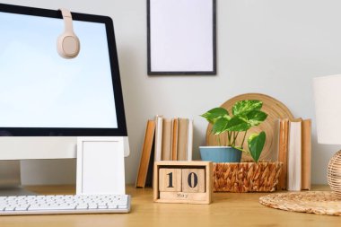 10 Mayıs tarihli küp takvimi, modern bilgisayar, boş resim çerçevesi ve ahşap masadaki kitaplar