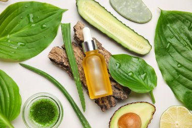 Kozmetik ürün şişesi, ağaç kabuğu ve beyaz arka plandaki malzemeler, yakın plan.