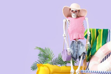 Leylak arka planında plaj aksesuarları olan insan iskeleti. Yaz tatili kavramı