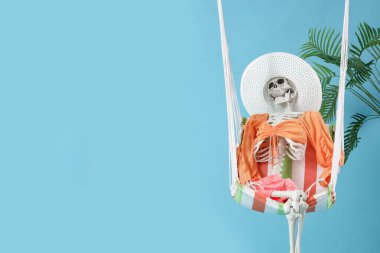 Hamakta giysileri ve mavi arka planda palmiye yaprakları olan insan iskeleti. Yaz tatili kavramı