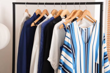 Beyaz duvarın yanında asılı giysilerle dizilin, kapatın.