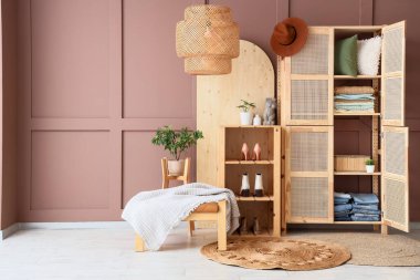 Odanın içindeki kahverengi duvarın yanında giysiler ve yastıklar olan ahşap dolabı aç.