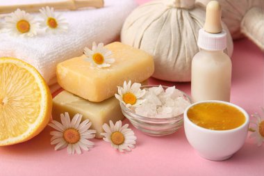 Papatya çiçekli spa kompozisyonu, ballı kâseler ve pembe arka planda yüz kremi, yakın plan.