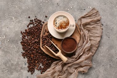Bir fincan kahve ile ahşap kepçe, fasulye ve toz gri grunge arka planda