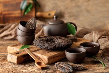 Çaydanlıklı kuru puer çayı ve ahşap arka planda fincanlar.