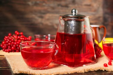 Cam bardaklar ve çaydanlık sıcak viburnum çayı ahşap arka planda.