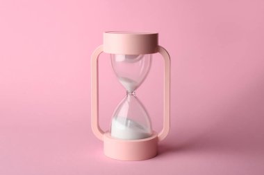 Pembe arka planda kristal kum saati