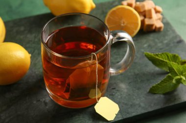 Yeşil grunge arka planda limon ve nane yapraklı bir fincan sıcak çay.