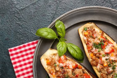 Yeşil grunge arka planda doldurulmuş patlıcan ve fesleğen yapraklı tabak.