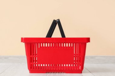 Bej duvarın yanında kırmızı alışveriş sepeti