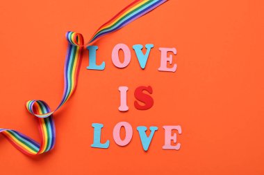Turuncu arka planda aşk mesajı olan gökkuşağı kurdelesi. LGBT kavramı
