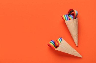 Turuncu arka planda gökkuşağı kurdeleli gözleme külahları. LGBT kavramı