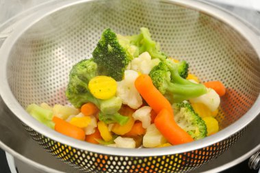 Metal kevgire buharda pişirilmiş sebzeler, yakın plan.