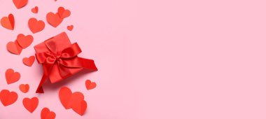 Hediye kutusu ve pembe arka planda kırmızı kağıt kalpler. Mesaj için yer var. Sevgililer Günü kutlaması