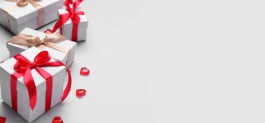 Sevgililer Günü kutlaması için hediye kutuları ve kalpler açık arkaplanda metin için yer var.