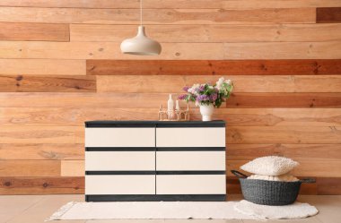 Şık çekmeceler ve sepet ve ahşap duvarın yanında yastıklar.