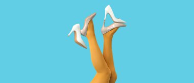 Tayt giymiş kadın bacakları ve mavi arka planda yüksek topuklu ayakkabı.