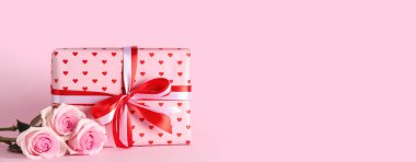 Pembe arka planda güzel güller ve hediye kutusu. Mesaj için yer var. Sevgililer Günü kutlaması