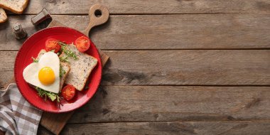 Lezzetli kalp şeklinde sahanda yumurta, tost, domates ve roka ile ahşap zemin üzerinde metin için boşluk.